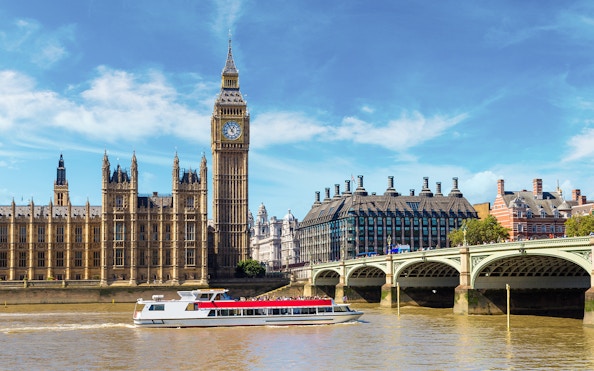 Westminster cruise boat on the Thames with Big Ben and bridge in view.