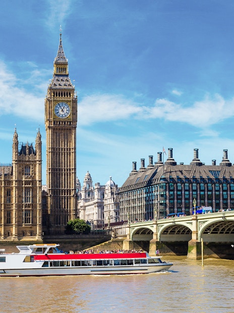 Westminster cruise boat on the Thames with Big Ben and bridge in view.