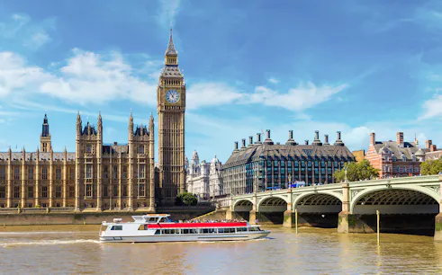 Westminster cruise boat on the Thames with Big Ben and bridge in view.