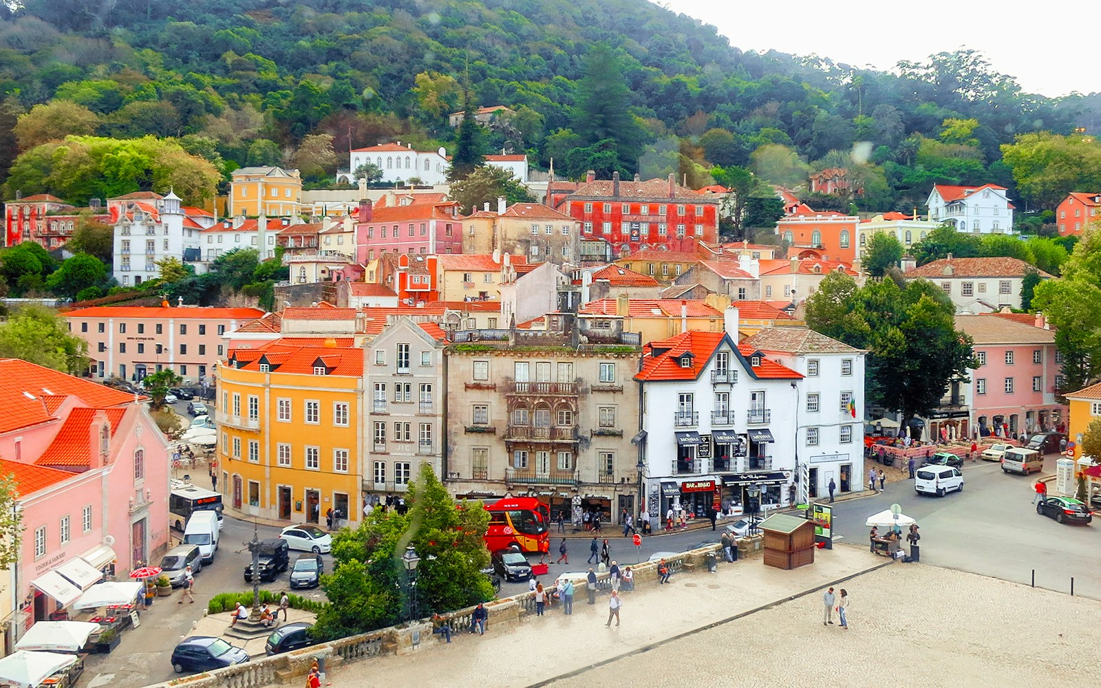 Colorful buildings and street in Sintra, Portugal, with lush hills in the background.