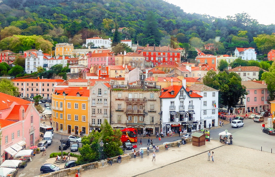 Colorful buildings and street in Sintra, Portugal, with lush hills in the background.