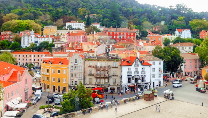 Colorful buildings and street in Sintra, Portugal, with lush hills in the background.