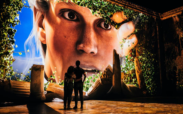 Couple viewing immersive Pompeia experience at IDEAL Barcelona with large digital display.