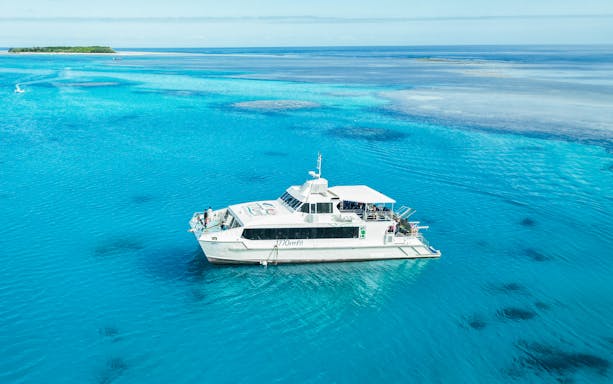 Boat approaching Lady Musgrave Island on a full day tour in clear blue waters.