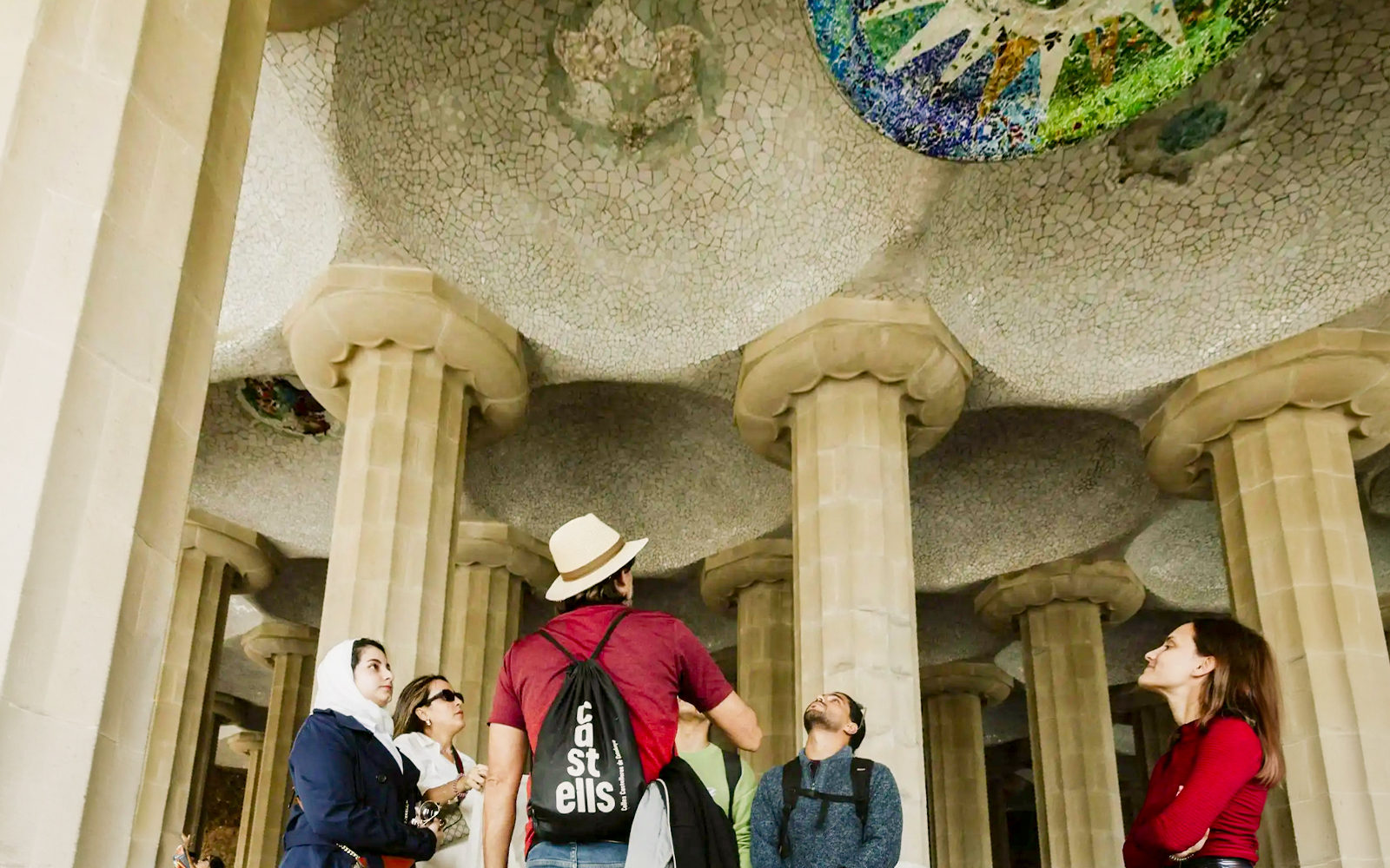Tourists with guide under mosaic ceiling at Park Güell, Barcelona.