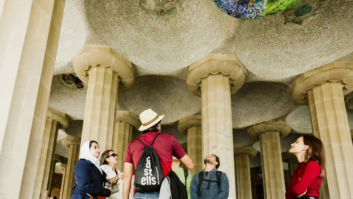 Tourists with guide under mosaic ceiling at Park Güell, Barcelona.
