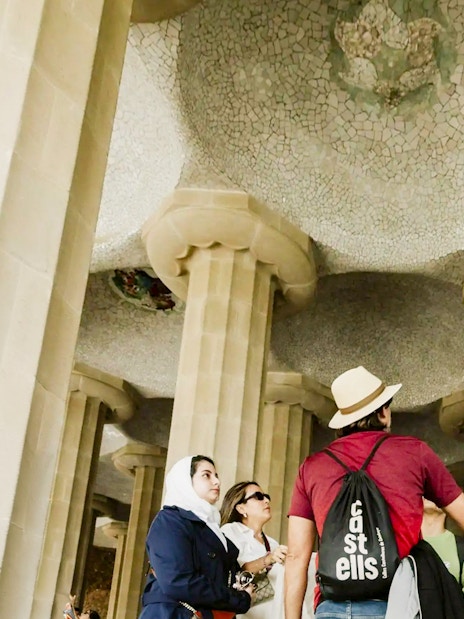 Tourists with guide under mosaic ceiling at Park Güell, Barcelona.