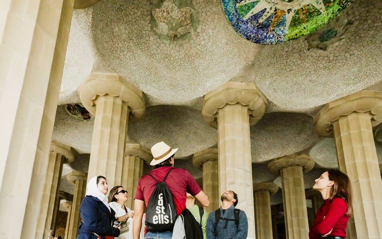 Tourists with guide under mosaic ceiling at Park Güell, Barcelona.