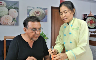 Master carver instructing student in Thai fruit carving at Penthouse Studio.