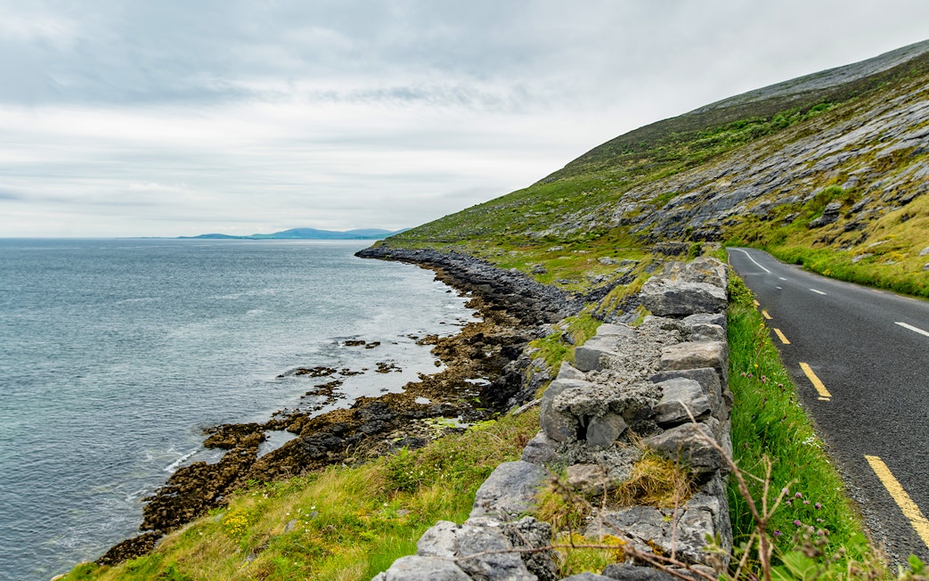 Coastal road alongside exposed karst limestone bedrock at Burren National Park, Ireland.