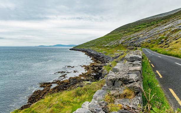 Coastal road alongside exposed karst limestone bedrock at Burren National Park, Ireland.