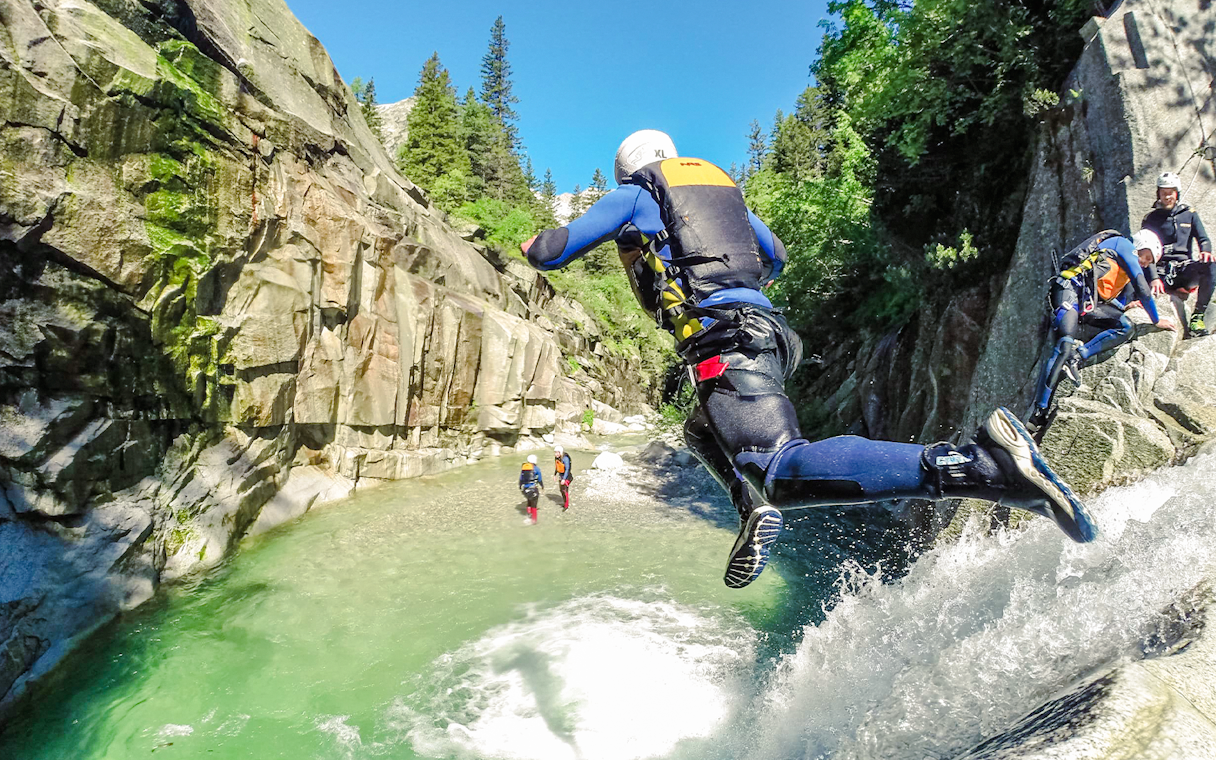 Adventurer jumping into a canyon river during a canyoning tour in Interlaken.