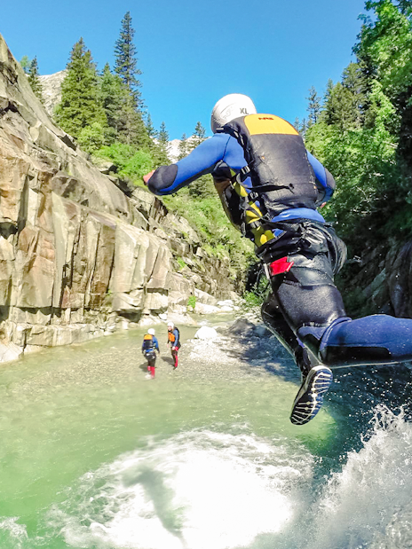 Adventurer jumping into a canyon river during a canyoning tour in Interlaken.
