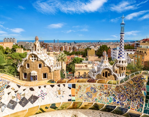 Park Güell's colorful mosaic terrace overlooking Barcelona cityscape.