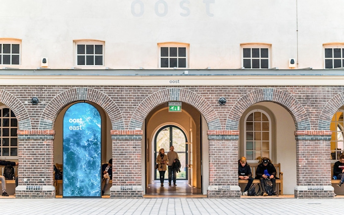Skylight view inside The Maritime Museum, Amsterdam, featuring brick arches and visitors.