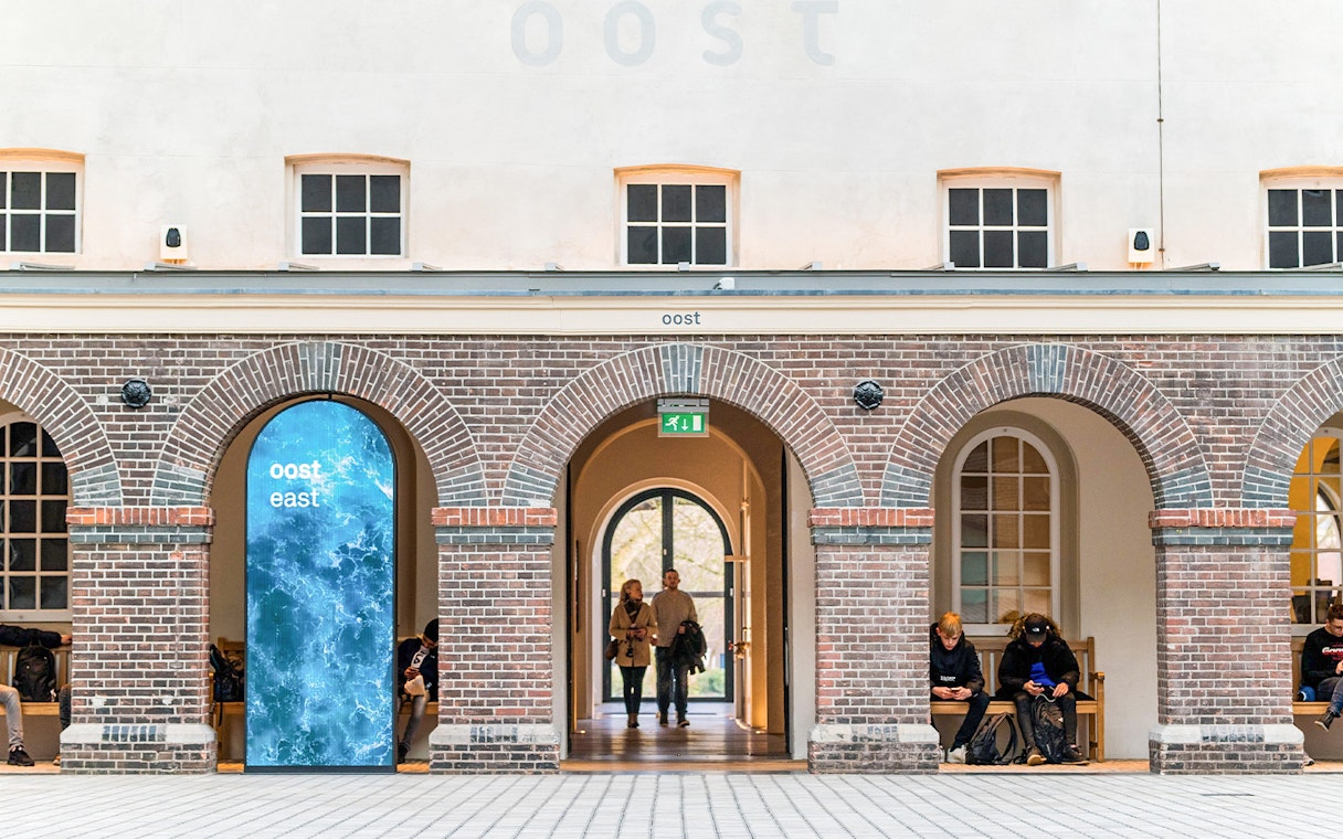 Skylight view inside The Maritime Museum, Amsterdam, featuring brick arches and visitors.