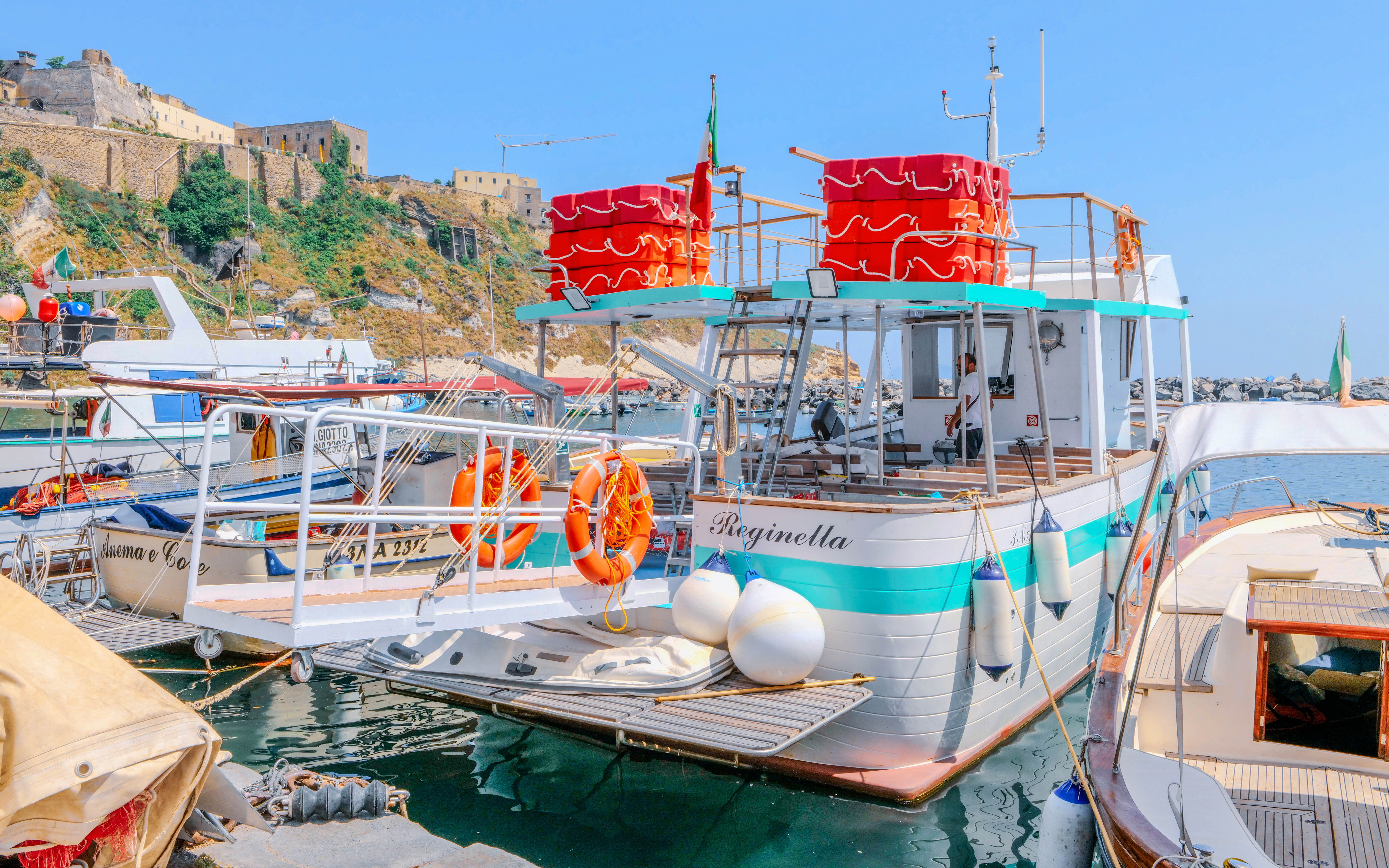 Boat docked at Procida Island with historic buildings in the background.