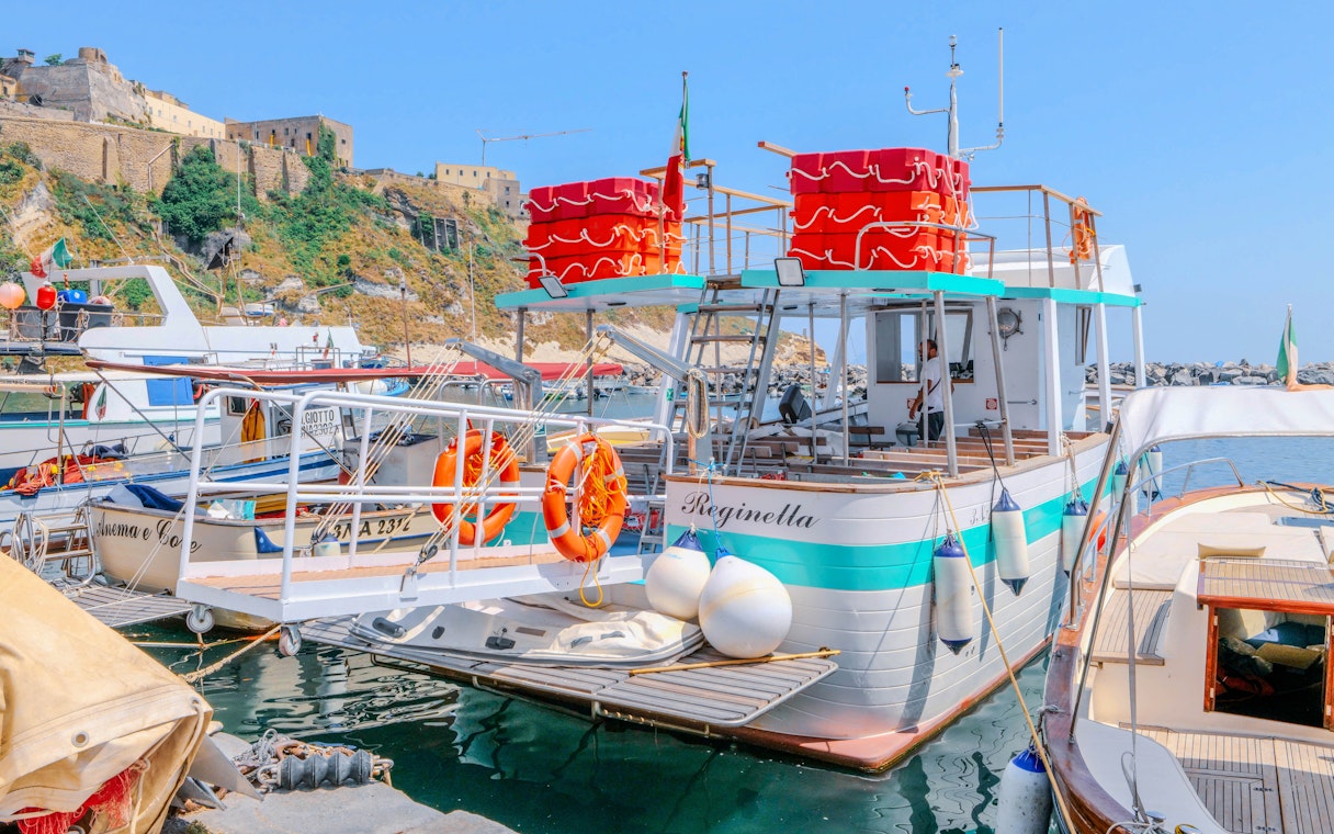Boat docked at Procida Island with historic buildings in the background.
