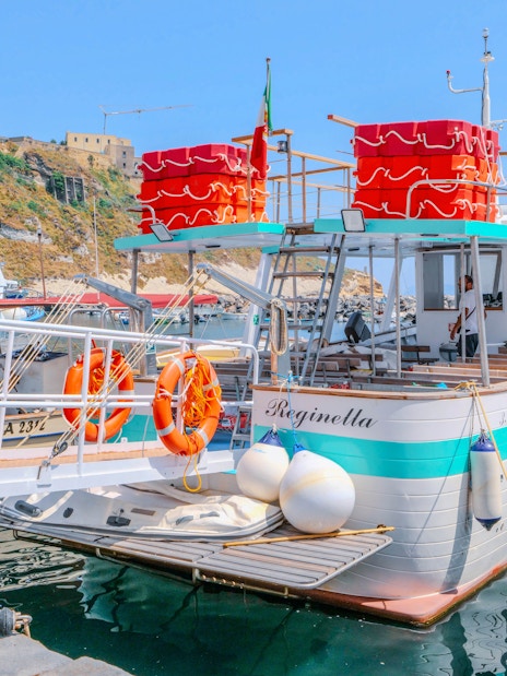 Boat docked at Procida Island with historic buildings in the background.