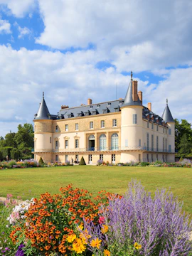 Castle of Rambouillet with gardens and colorful flowers in the foreground.