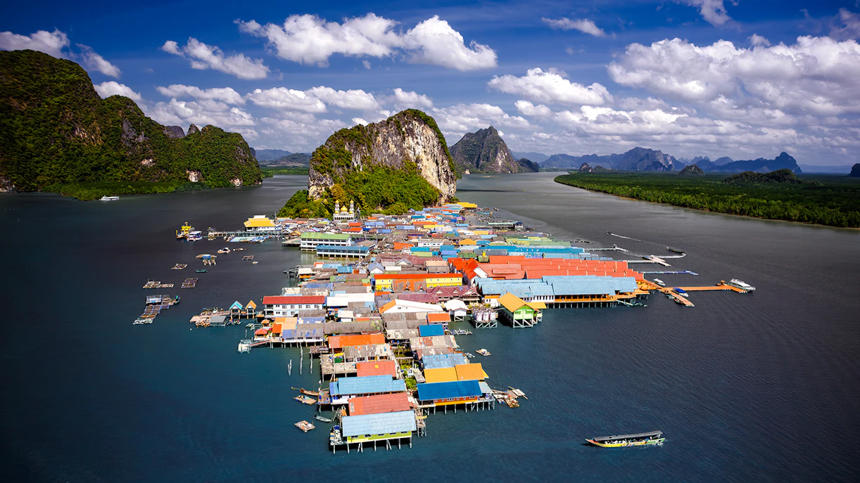 Aerial view of Koh Panyee, Thailand's floating village with colorful houses and limestone cliffs.