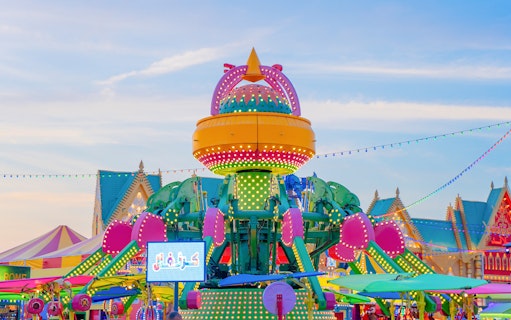 Colorful amusement ride at Global Village Dubai with vibrant lights and festive decorations.