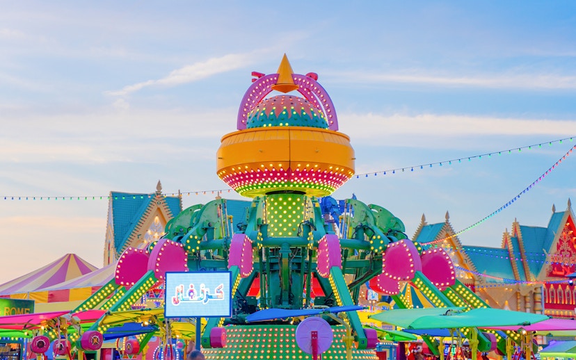 Colorful amusement ride at Global Village Dubai with vibrant lights and festive decorations.