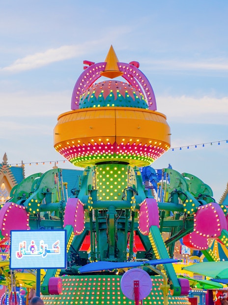 Colorful amusement ride at Global Village Dubai with vibrant lights and festive decorations.