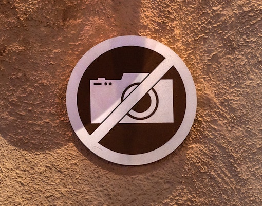 No photography sign on textured wall.