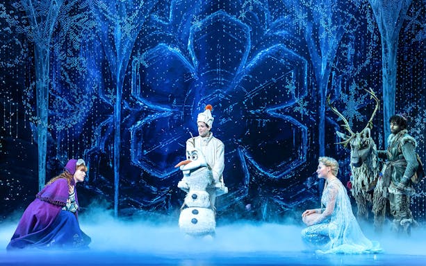 Characters from Disney FROZEN musical on stage with snowy backdrop.