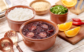 Feijoada with rice, greens, and orange slices on Rio de Janeiro food tour.