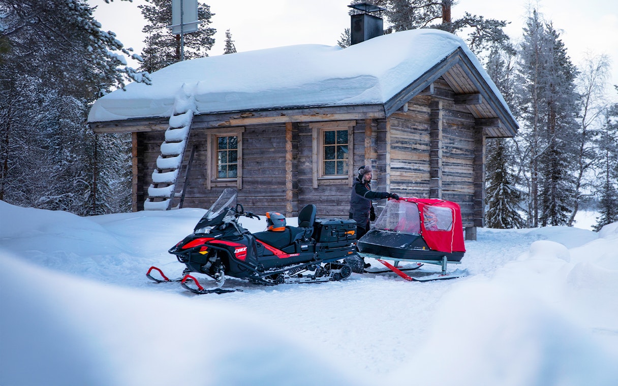 Snowmobile parked outside snowy cabin during Northern Lights tour.