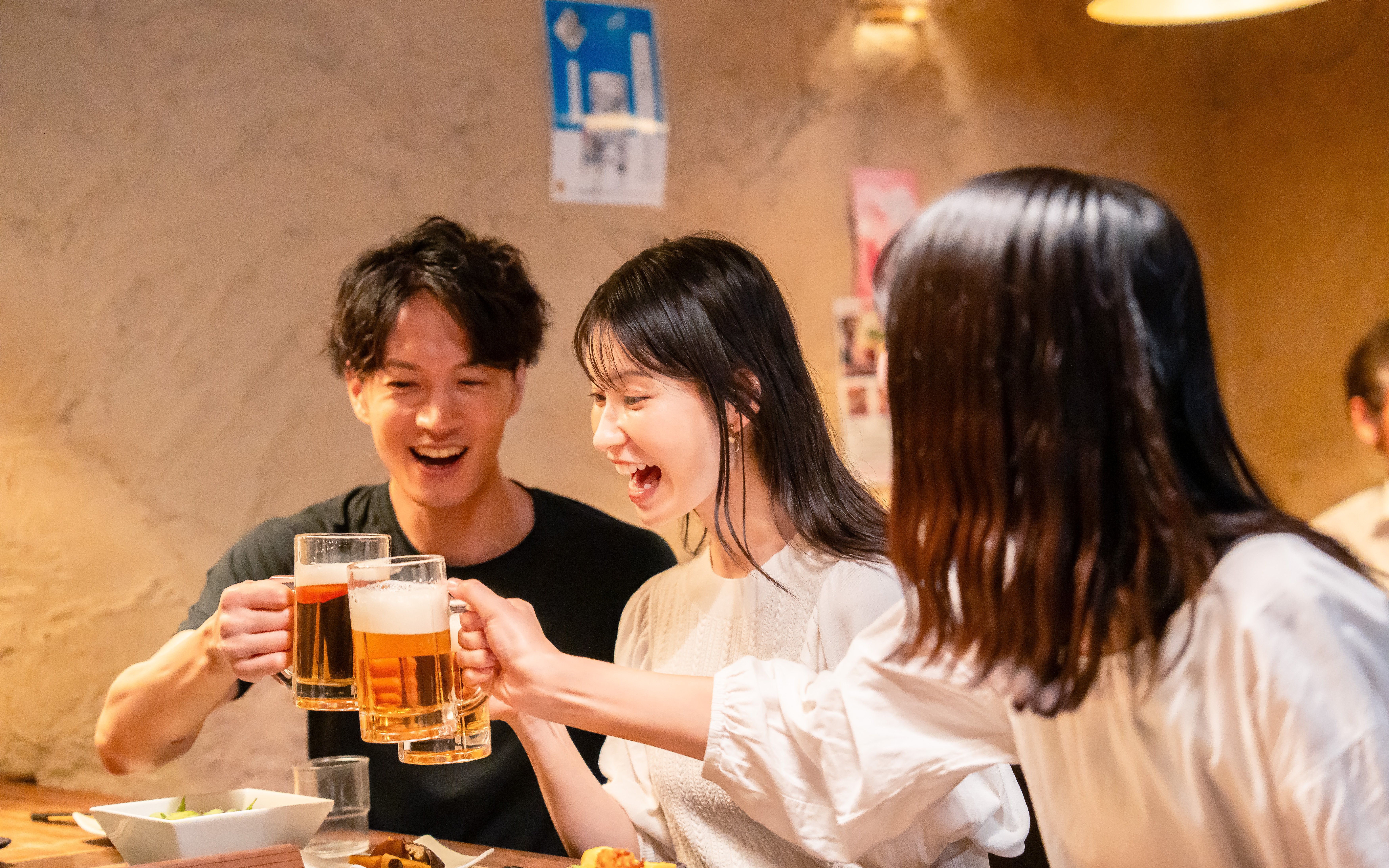 Young adults enjoying drinks at a Japanese izakaya.