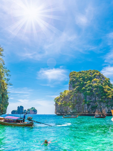 Longtail boats in Loh Samah Bay, Phi Phi, with limestone cliffs and clear water.