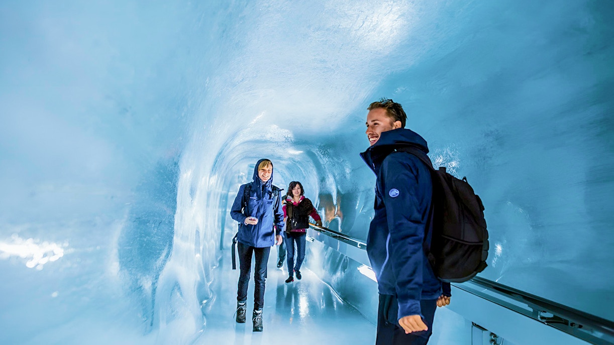 Visitors walking through an ice tunnel on the Schilthorn Cable Car trip from Geneva to Interlaken.