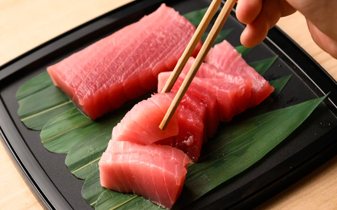 Tuna slices on a leaf with chopsticks, part of Tsukiji Market tour.