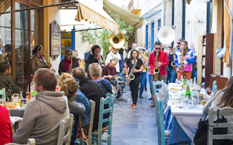 Musicians performing in a jazz festival parade through narrow streets of a Greek village.