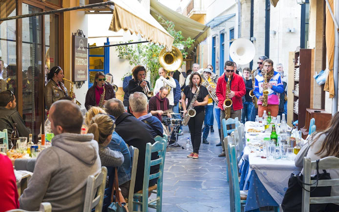 Musicians performing in a jazz festival parade through narrow streets of a Greek village.