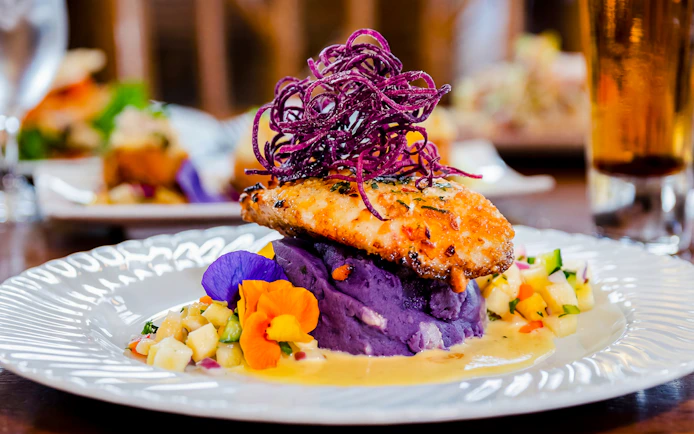 Grilled fish on purple mashed potatoes with pineapple salsa, part of Pineapple Farm Tour & Gourmet Dining Experience.