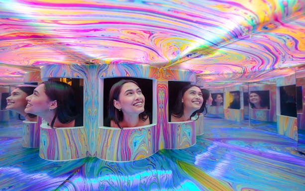 Guests exploring colorful mirrored exhibits at the Twist Museum in London.