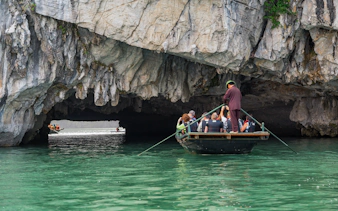 Tourists on a flat boat entering Hang Luon Cave in Halong Bay, Hanoi, Vietnam.