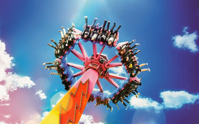Thrill ride at Ocean Park with people on a spinning attraction against a blue sky.