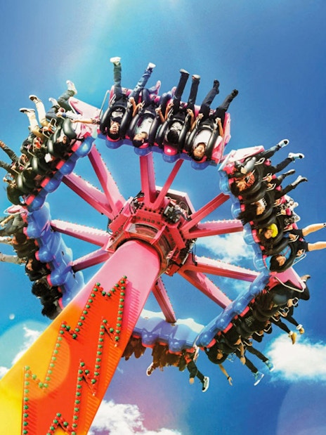Thrill ride at Ocean Park with people on a spinning attraction against a blue sky.