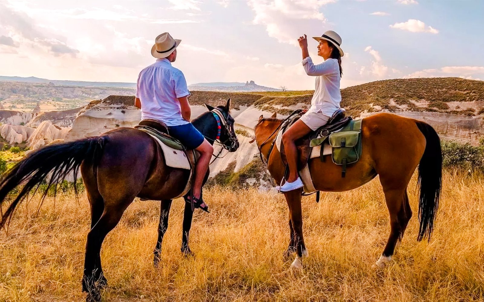 Guests horseback riding at sunset in Cappadocia with scenic rock formations.