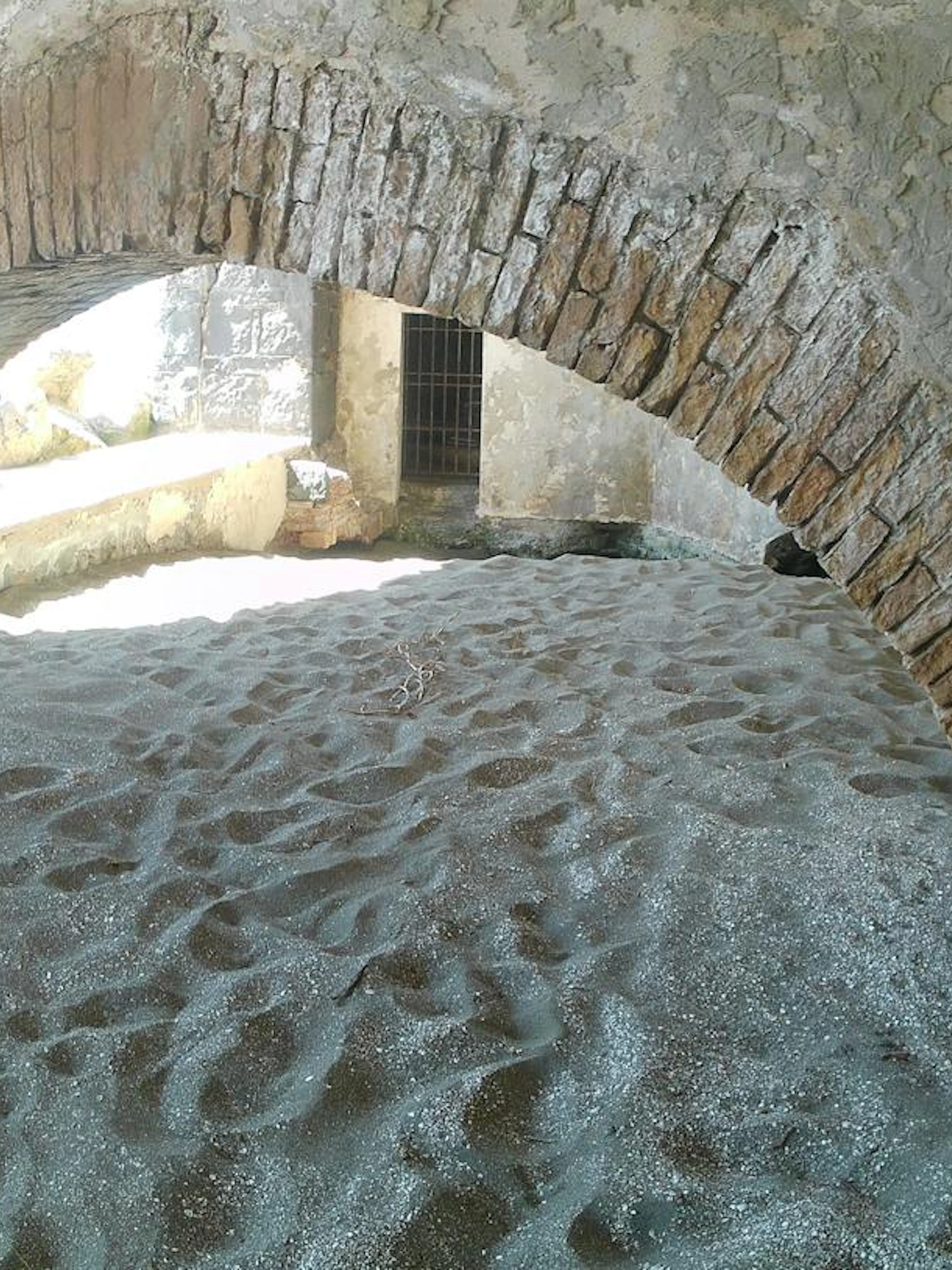 Ancient brick archway on sandy beach, Posillipo Coast, Naples.