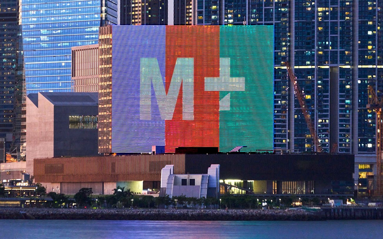 M+ Museum facade with colorful digital display in Hong Kong skyline.