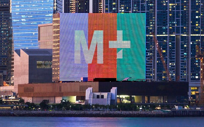 M+ Museum facade with colorful digital display in Hong Kong skyline.