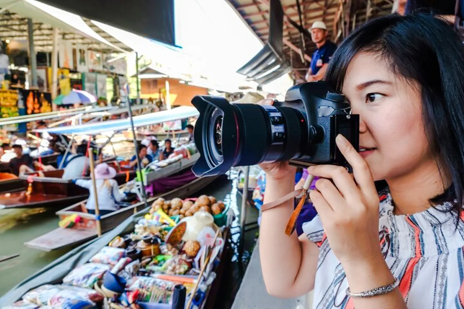Tourist photographing boats at Amphawa Floating Markets during private tour from Laem Chabang, Pattaya.