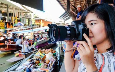 Tourist photographing boats at Amphawa Floating Markets during private tour from Laem Chabang, Pattaya.