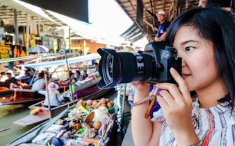 Tourist photographing boats at Amphawa Floating Markets during private tour from Laem Chabang, Pattaya.